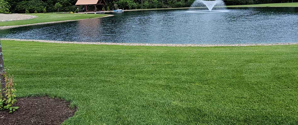 Beautiful, green lawn near a pond with a water feature in Hinckley, OH.
