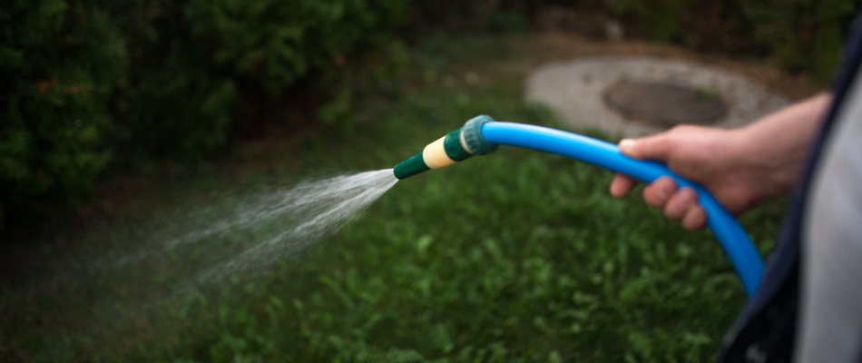 Professional applying liquid fertilizer from blue hose in Wadsworth, OH.